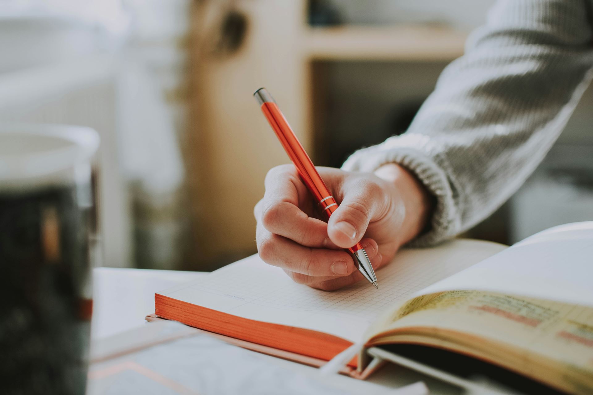 hand holding orange pen on diary